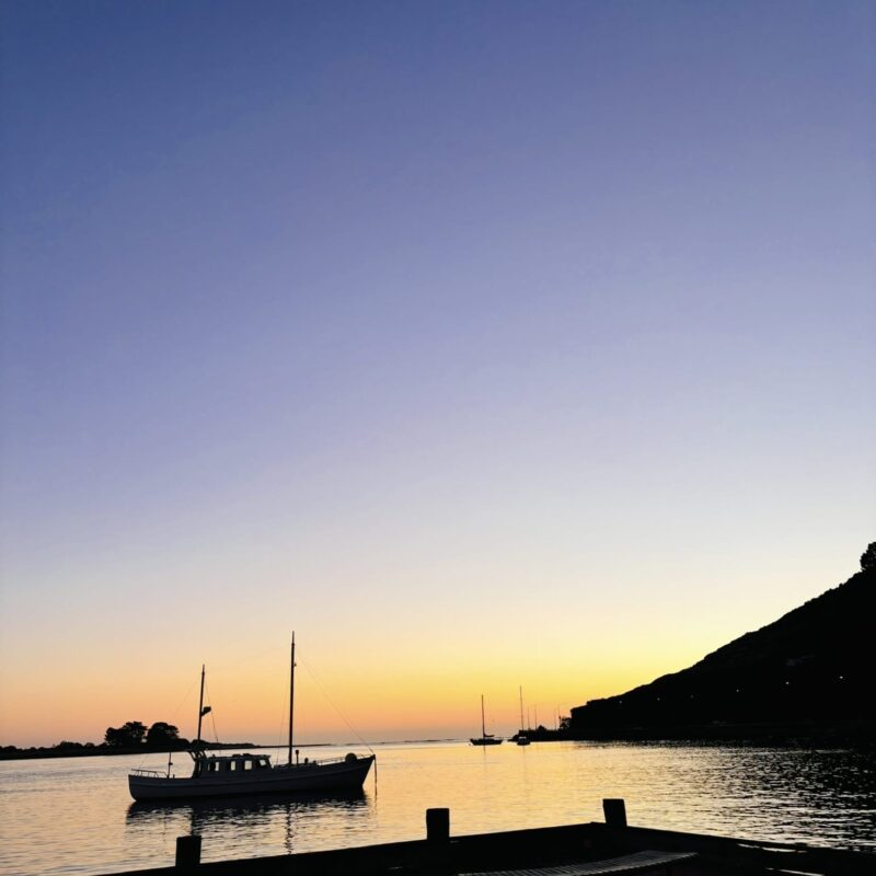 Sunset in Sumner bay looking out at a sail boat in Christchurch